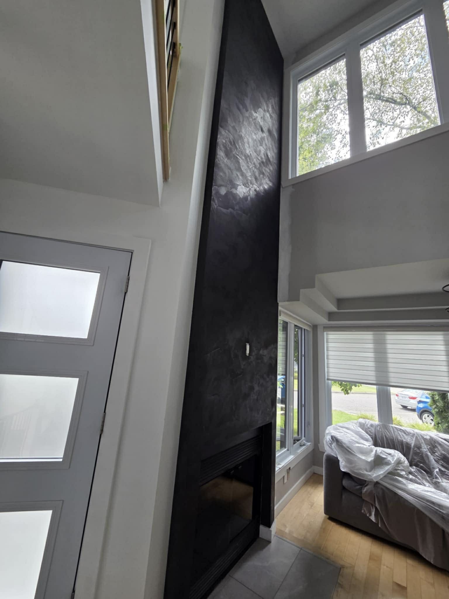 Application d’enduit décoratif foncé sur mur d’accent